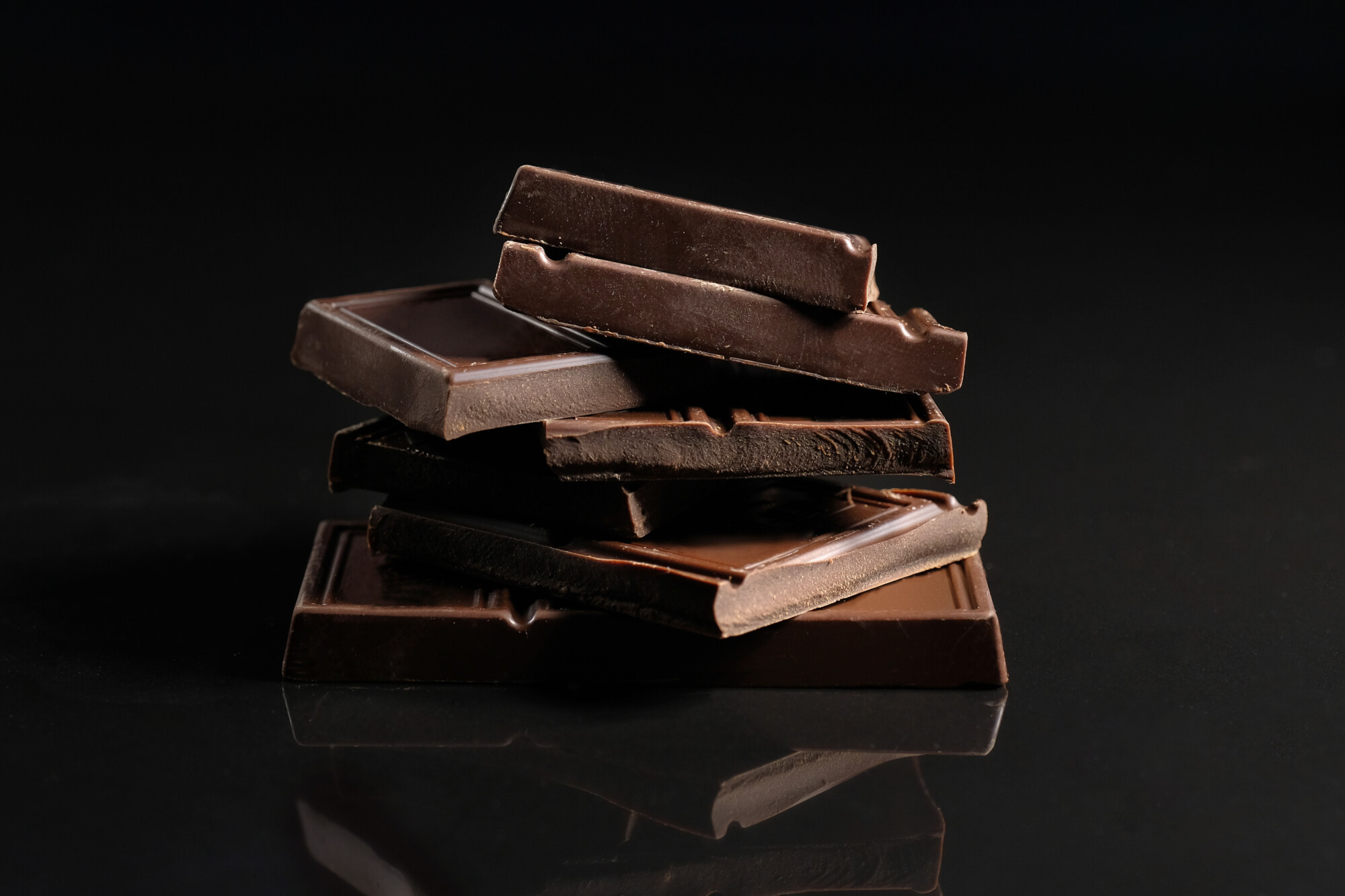 Broken chocolate pieces on a black background. Close-up